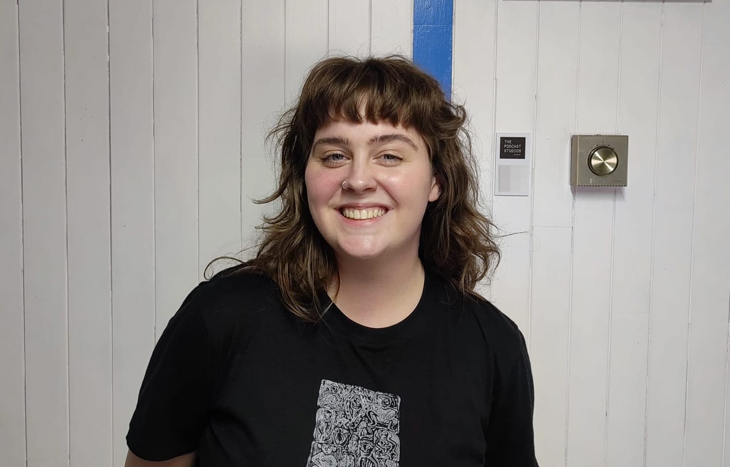 Megan Nyhan, a young woman in a black T-shirt, pictured in the The Podcast Studios.